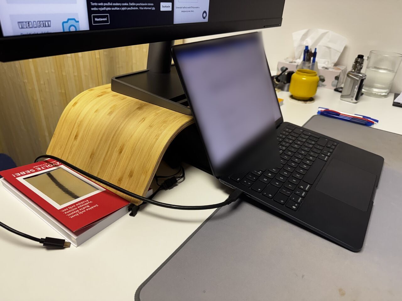 MacBook Air ležící zadní hranou na tištěném chladicím tunelu pod stojanem monitoru, přední hrana zůstává na stole